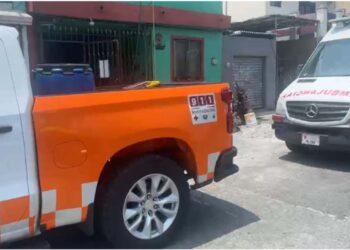 Fotografía de una calle en Guadalupe Nuevo León. Hay dos automoviles estacionados, una camioneta blanca con naranja y detras una ambulancia