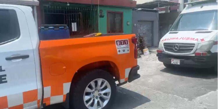 Fotografía de una calle en Guadalupe Nuevo León. Hay dos automoviles estacionados, una camioneta blanca con naranja y detras una ambulancia